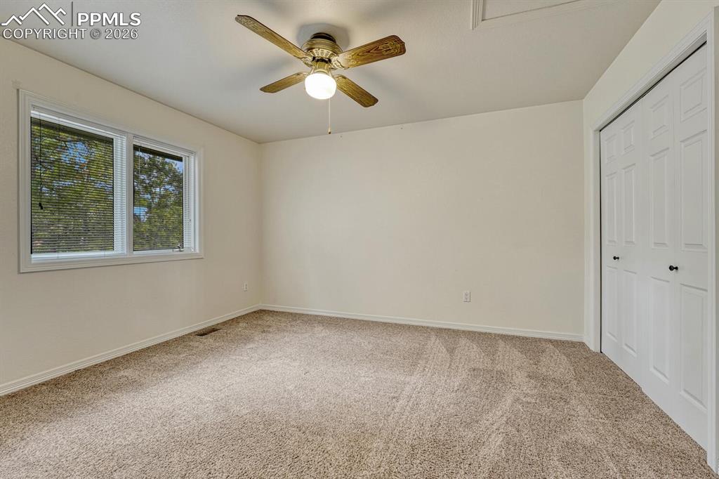 Upper Level Bedroom with neutral carpet and lighted ceiling fan.