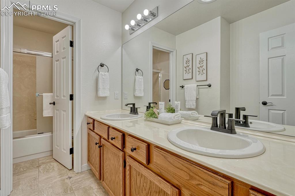 Upper Level Full Hall Bathroom with dual sink vanity, mirror, and tiled tub/shower.