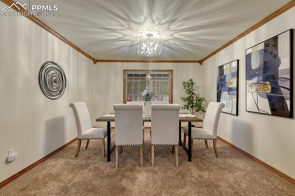 The Formal Dining Room features plush carpet, crown molding, & a beautiful chandelier, perfect for entertaining guests and family.