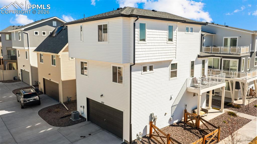 Back of property with an attached garage, a balcony, driveway, and a patio area