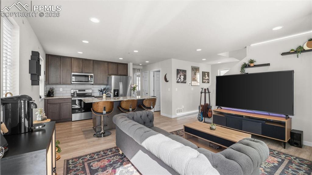 Living room with light wood-type flooring and recessed lighting