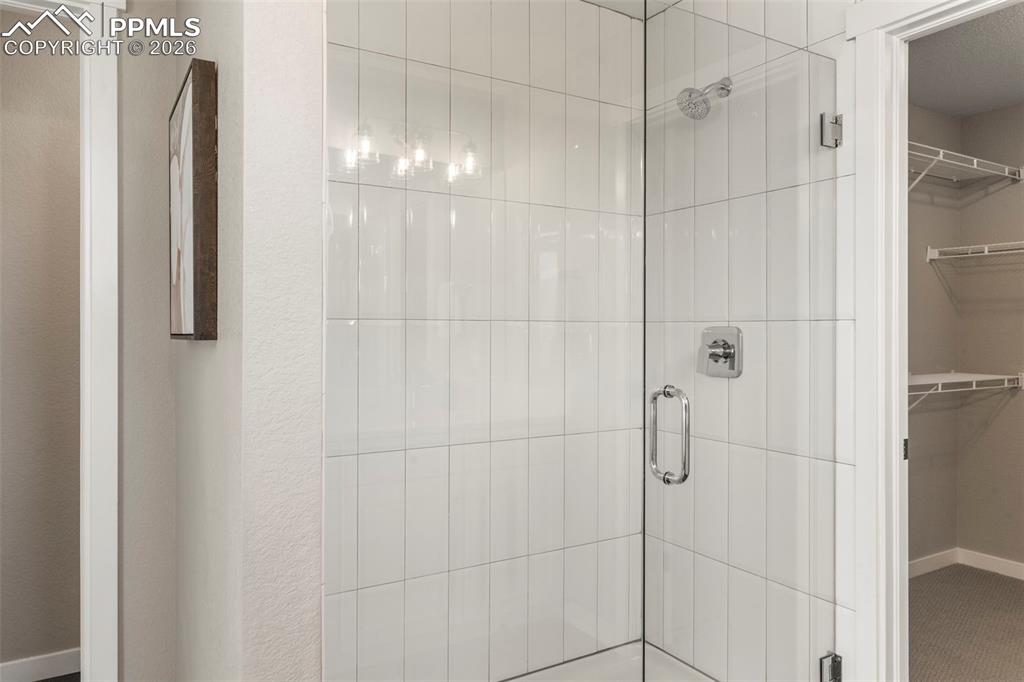 Frameless glass shower with decorative tile in primary suite 
