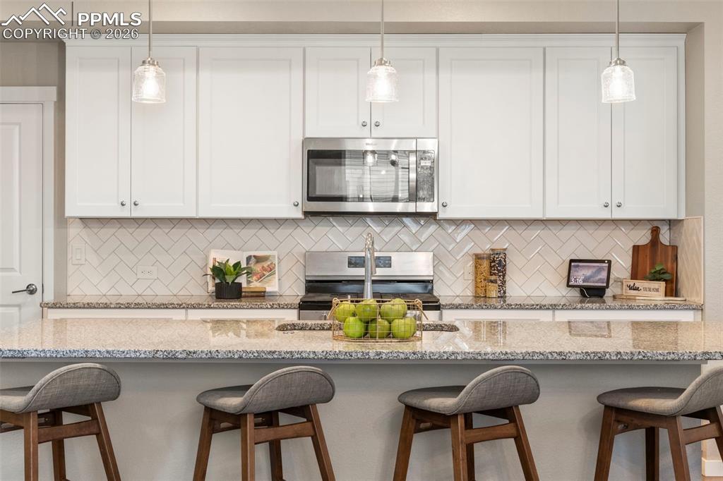 Extra long kitchen island with granite counters, herringbone backsplash, soft close cabinetry