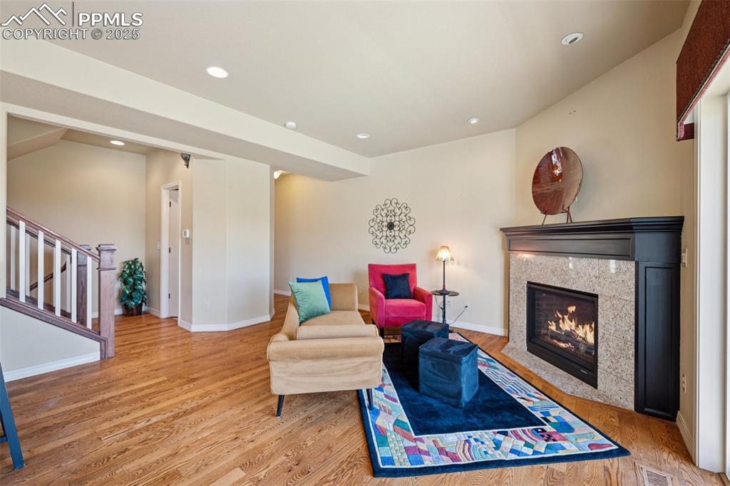 Living area featuring wood finished floors, a premium fireplace, stairway, and recessed lighting