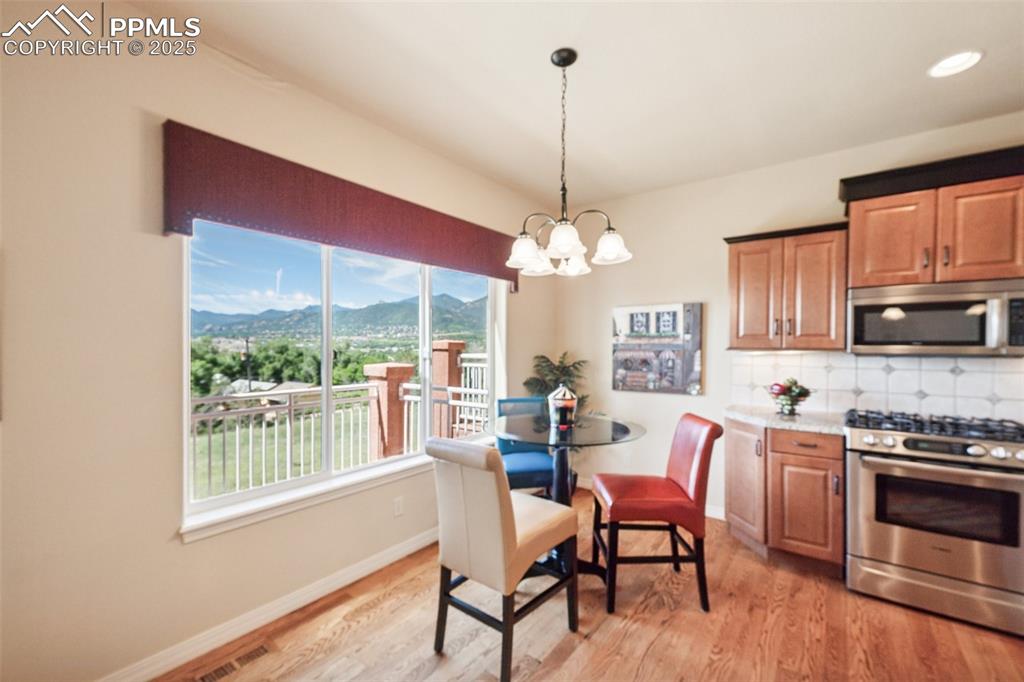 Kitchen featuring appliances with stainless steel finishes, a chandelier, a mountain view, tasteful backsplash, and light wood-style floors