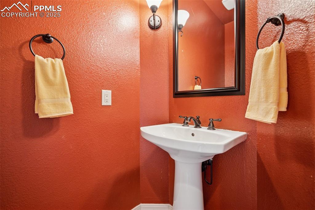 Main level 1/2 Bathroom featuring a sink and a textured wall
