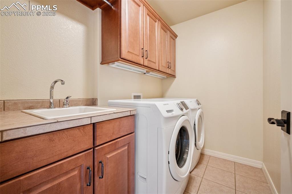 Laundry room with cabinet space, separate washer and dryer, and light tile patterned floors