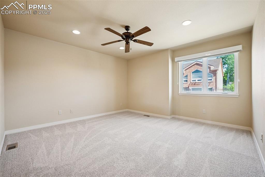 Carpeted empty room featuring a ceiling fan and recessed lighting