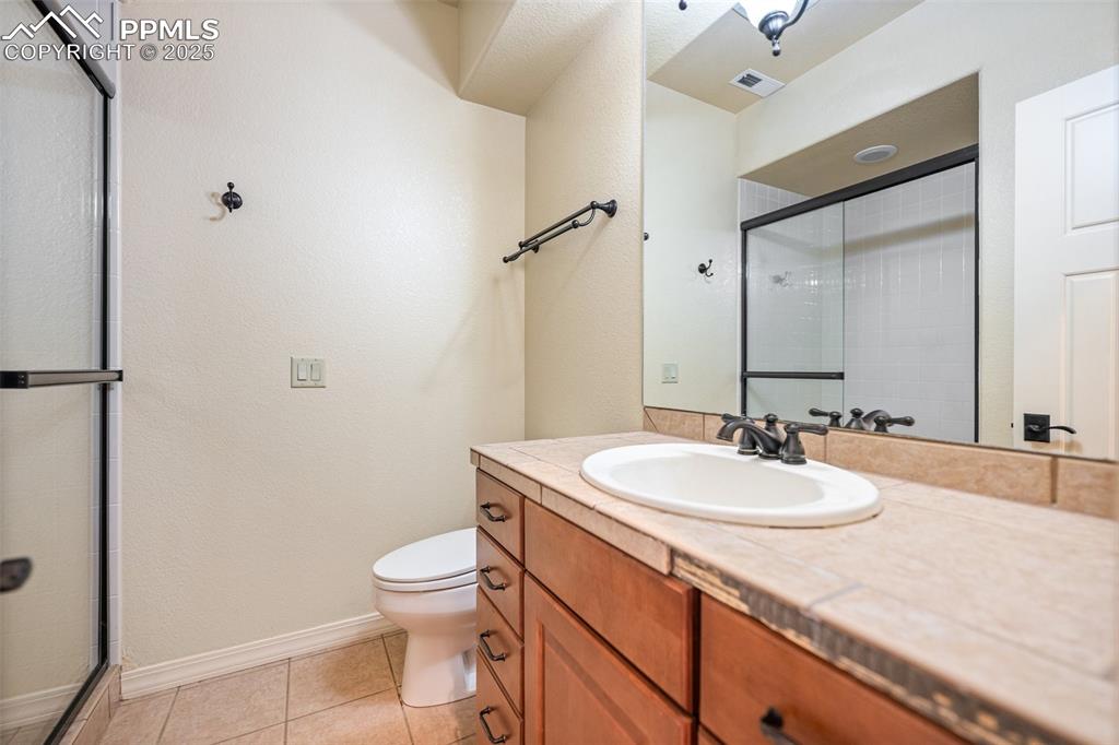 Bathroom featuring vanity, an enclosed shower, and tile patterned flooring