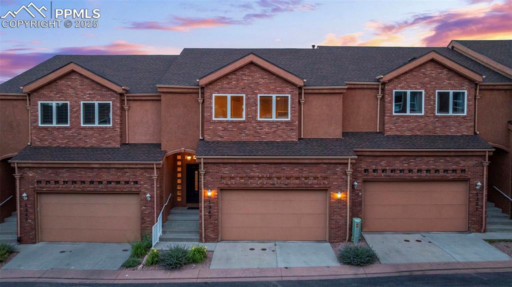 View of front facade featuring a garage, concrete driveway, and brick siding