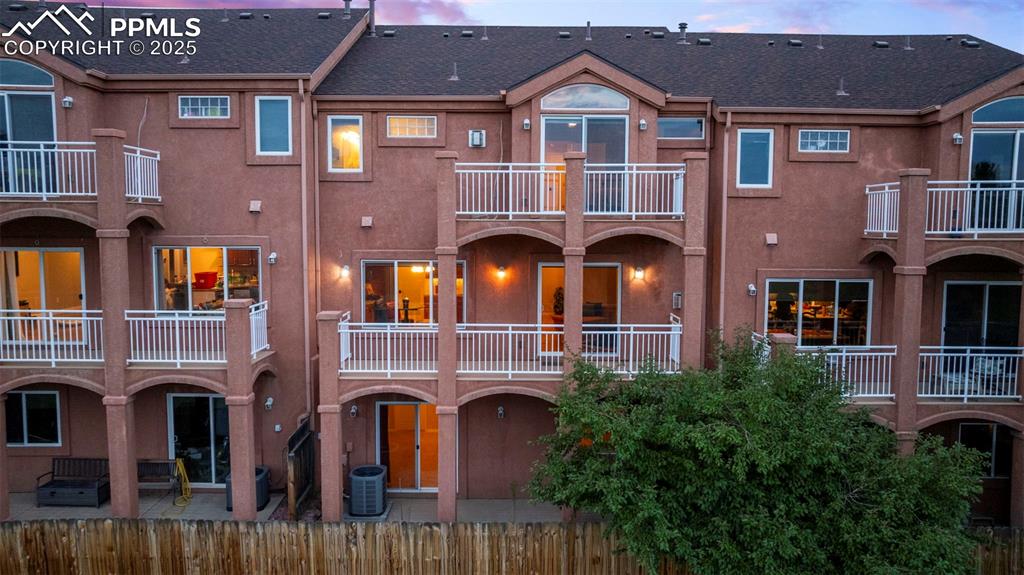 Back of house featuring stucco siding, a balcony, a patio area, and roof with shingles