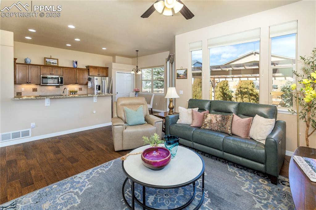 Living area with ceiling fan, dark wood-style floors, and a chandelier