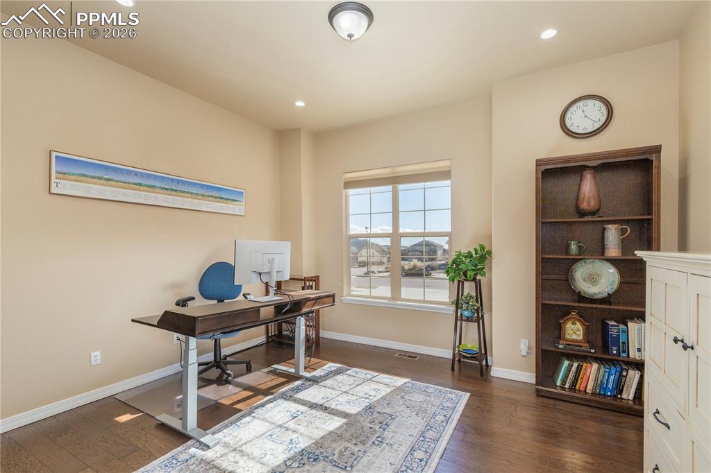 Office space with dark wood-type flooring and recessed lighting
