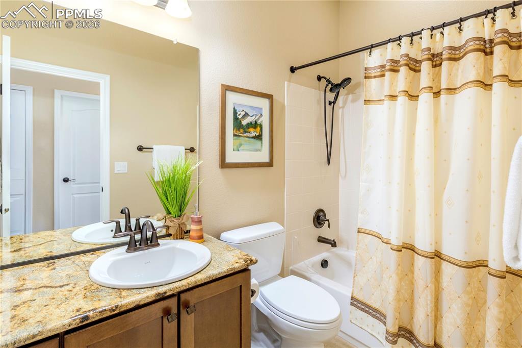 Main-level full bathroom features maple vanity, granite counter and tub/shower combination with oil-rubbed bronze finishes.
