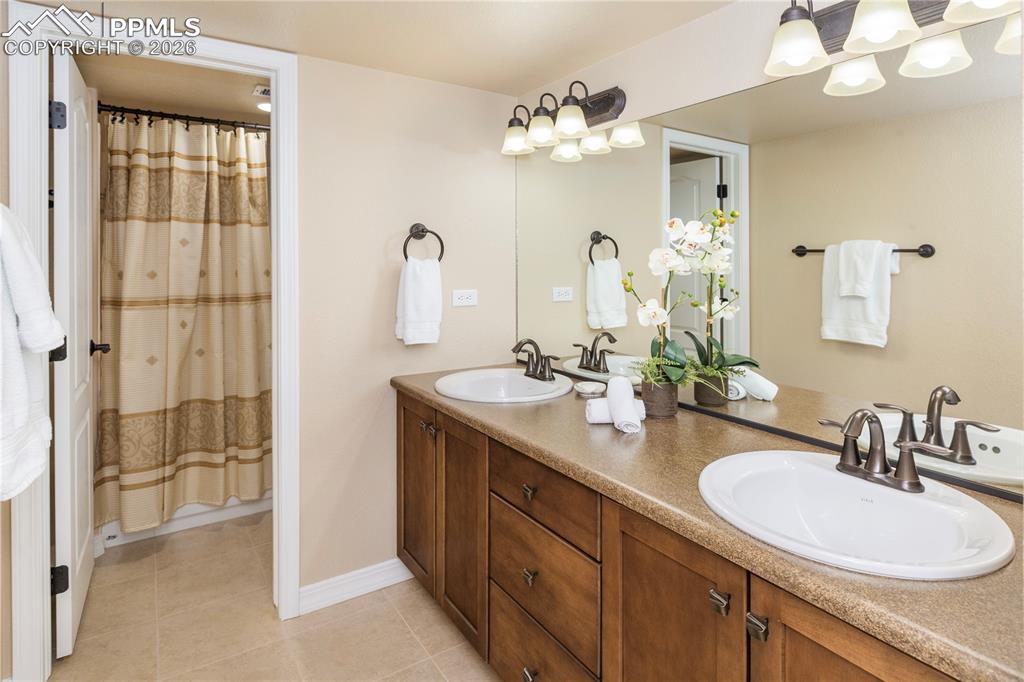 Full bathroom features double vanity, tub/shower combination, maple cabinetry and a linen closet.