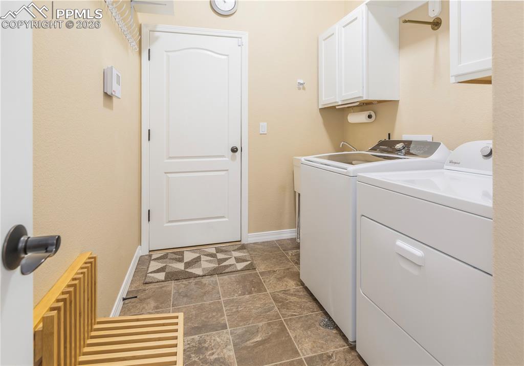 Laundry room features overhead storage, Whirlpool washer (2026) and dryer (2018), and a folding wood bench to remove/put on shoes.