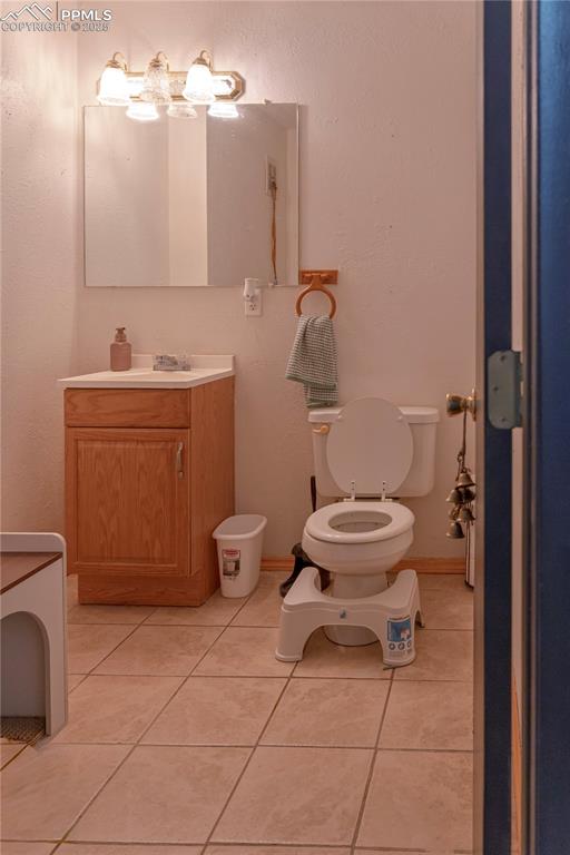 Half bathroom with vanity, light tile patterned floors, and a textured wall
