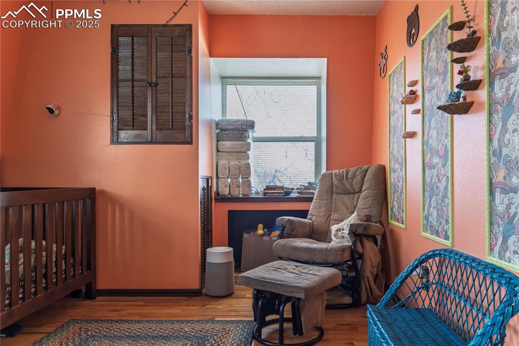 Bedroom with a crib, wood finished floors, and a textured ceiling