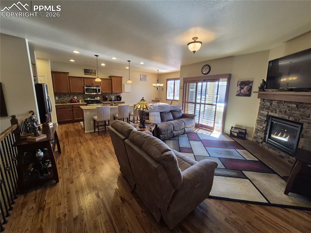 Living area with dark wood-style floors, a fireplace, a textured ceiling, and a chandelier
