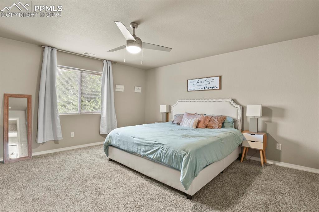 Carpeted bedroom with a ceiling fan and a textured ceiling