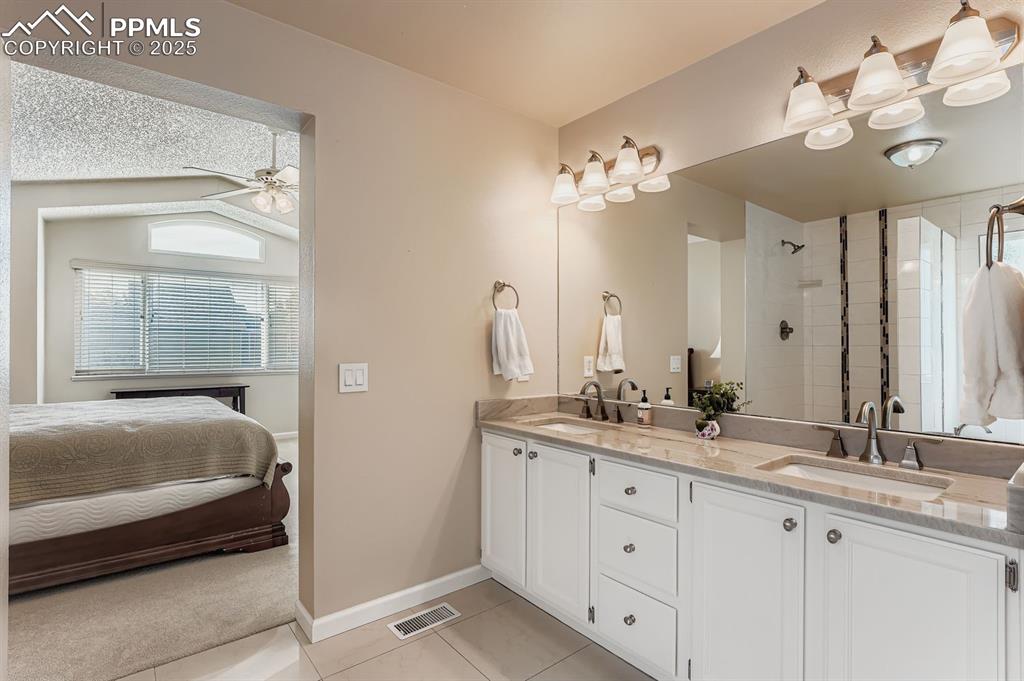 Ensuite bathroom with light tile patterned flooring, double vanity, a shower stall, and ceiling fan