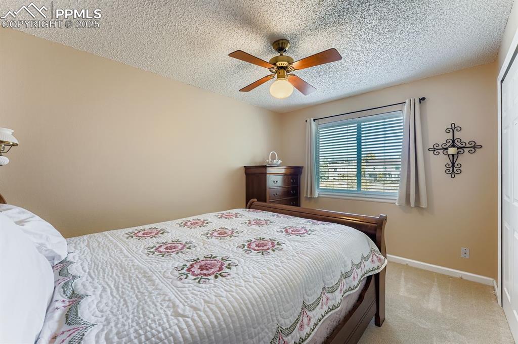 Bedroom featuring carpet floors, ceiling fan, a textured ceiling, and a closet