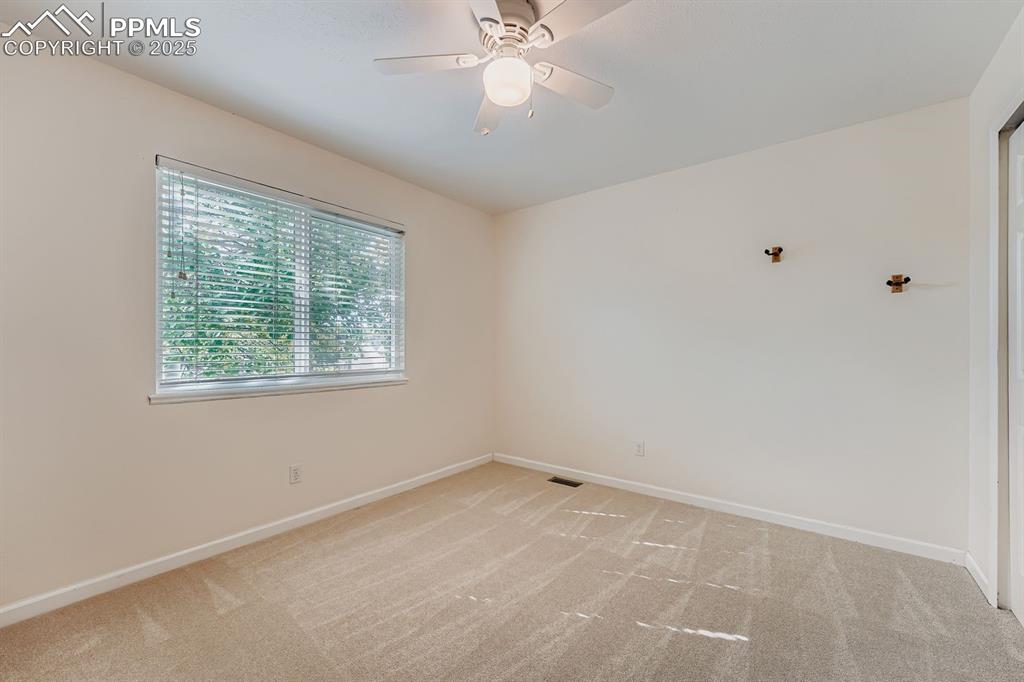 Empty room with light carpet and a ceiling fan