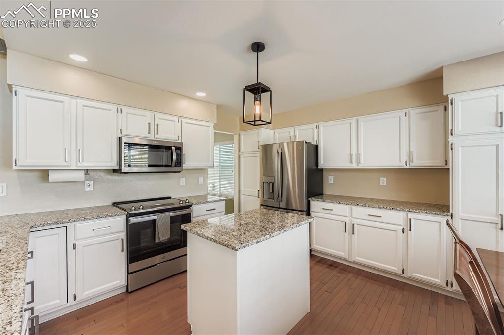 Kitchen featuring stainless steel appliances, white cabinetry, a center island, pendant lighting, and recessed lighting