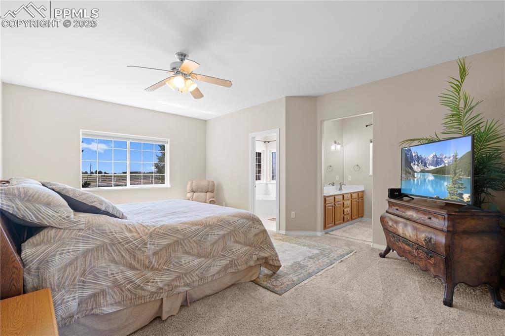 Bedroom with light carpet, ensuite bath, and a ceiling fan