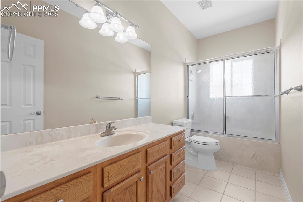 Full bathroom featuring vanity, tile patterned floors, and enclosed tub / shower combo