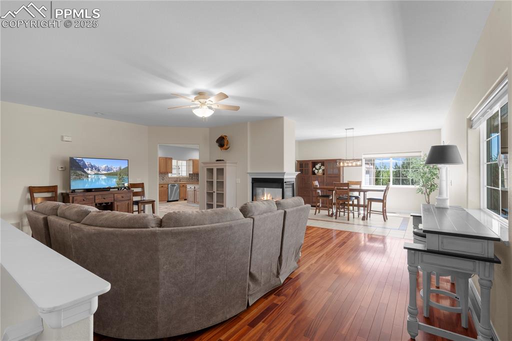 Living room with hardwood / wood-style flooring, ceiling fan, and a multi sided fireplace