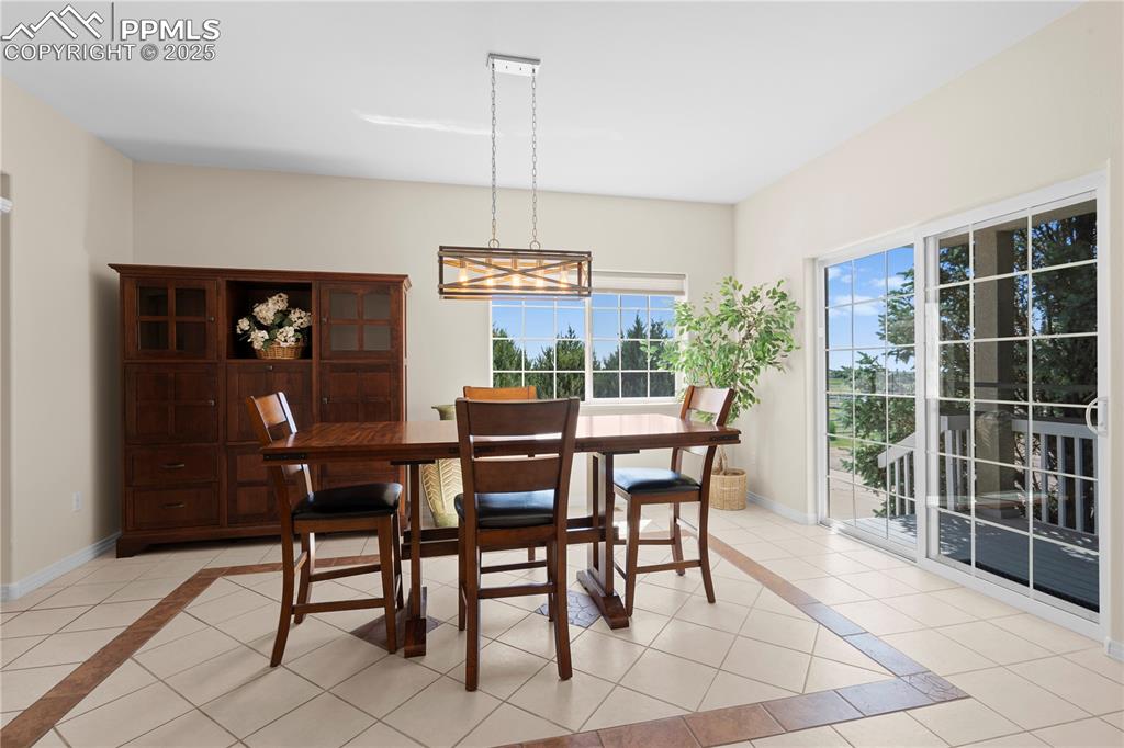 Dining space with light tile patterned floors, a chandelier, and inlaid floor details