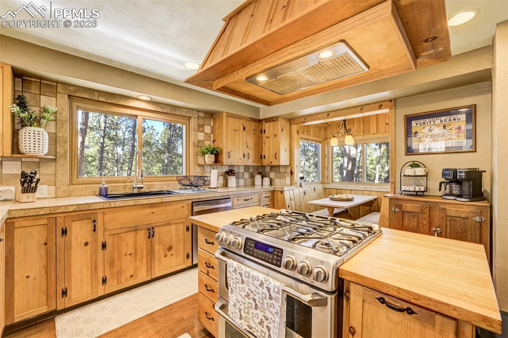 Kitchen featuring stainless steel gas stove, a center island, open shelves, light wood-style flooring, and backsplash