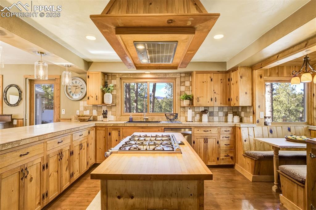 Kitchen featuring pendant lighting, butcher block countertops, a kitchen island, and a peninsula