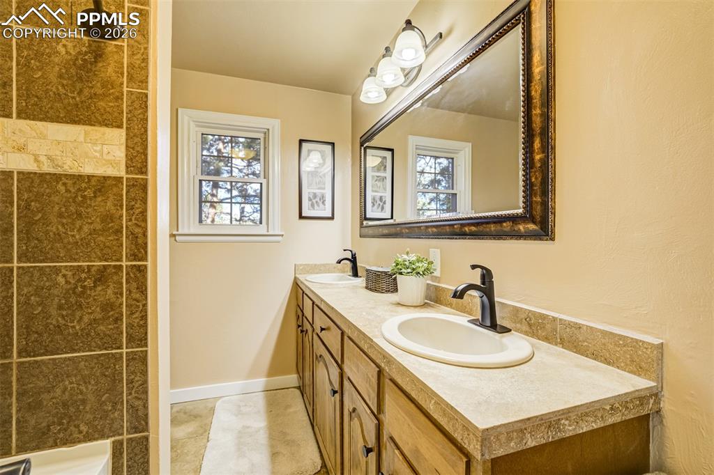 Main level full bathroom with double vanity and a shower