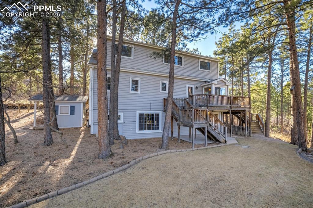 Rear view of property featuring stairs and a wooden deck