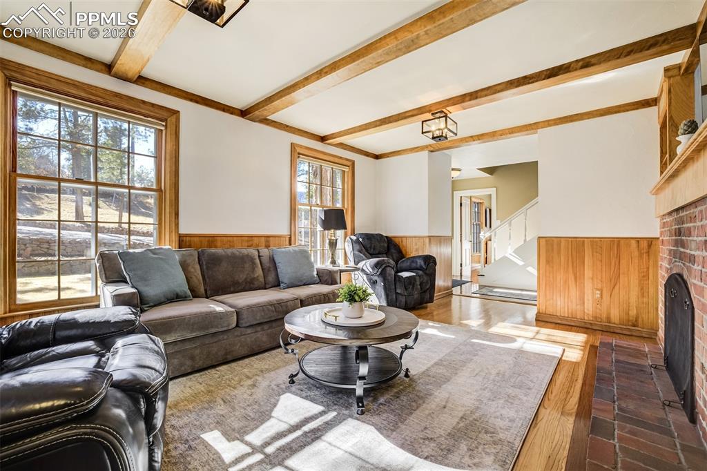 Main level living area with wood wainscoted wall, built in features, a fireplace, and beamed ceiling