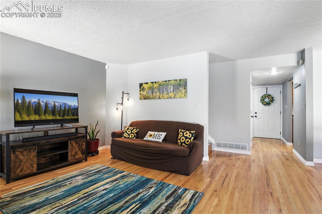 Living area with light wood-type flooring and a textured ceiling