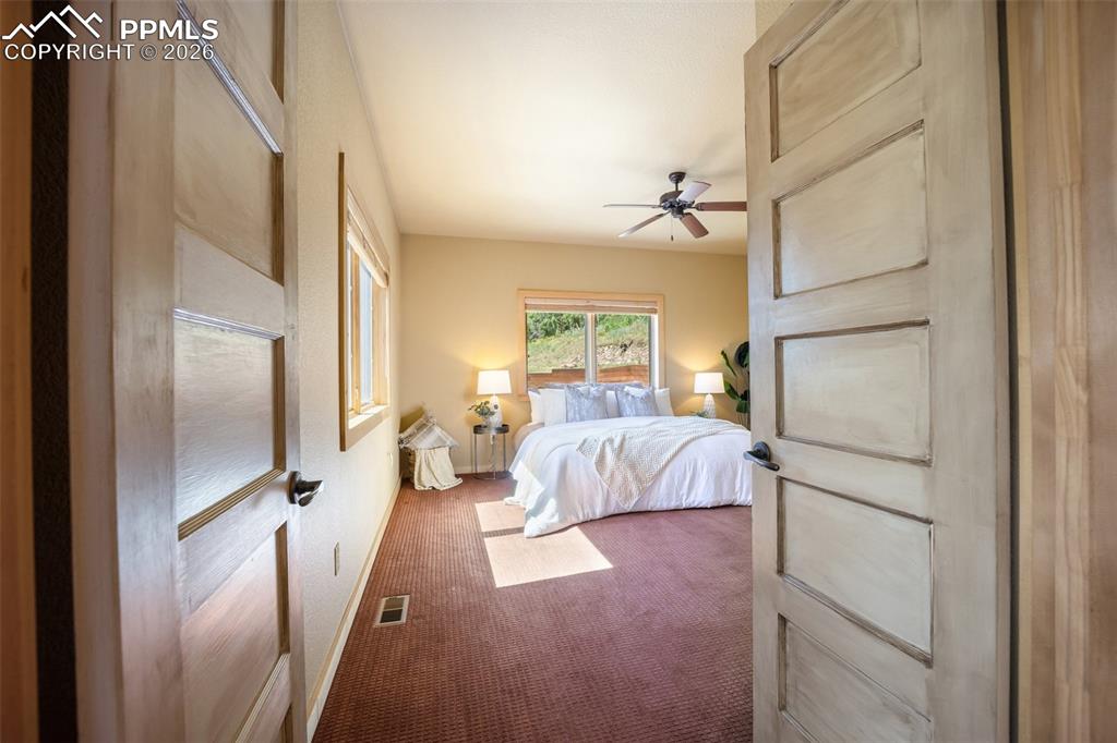 Carpeted bedroom featuring ceiling fan and baseboards