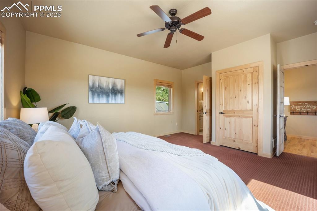 Bedroom with ensuite bathroom, a ceiling fan, and carpet flooring