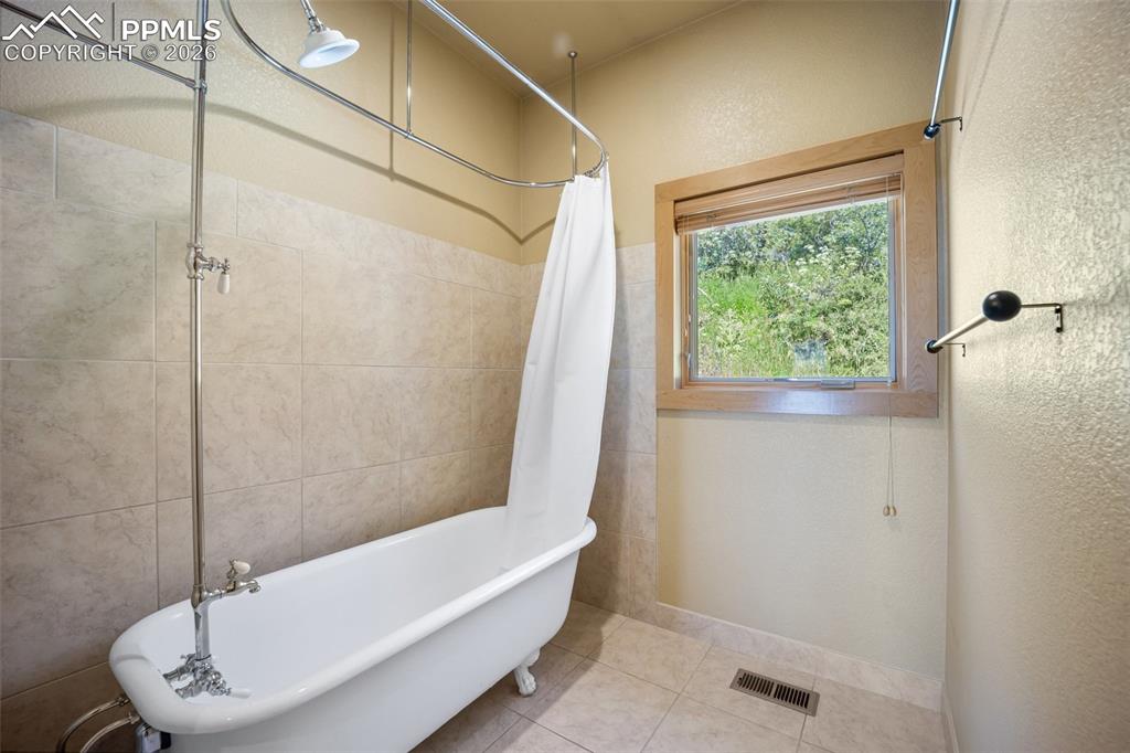Bathroom featuring a combined bath / shower with freestanding tub and light tile patterned floors