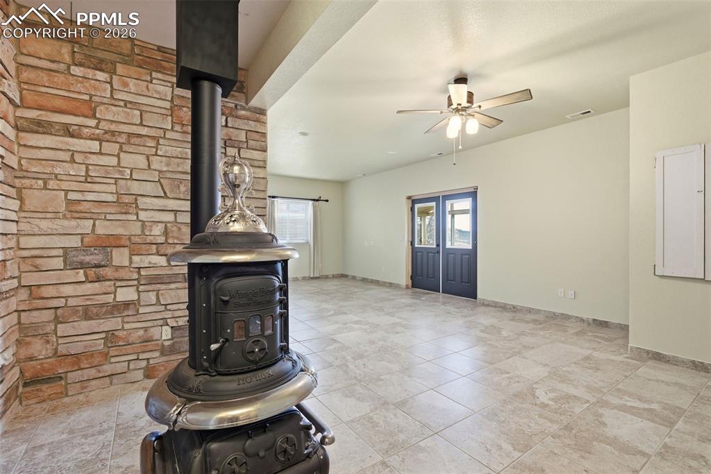 Unfurnished living room featuring a wood stove and a ceiling fan