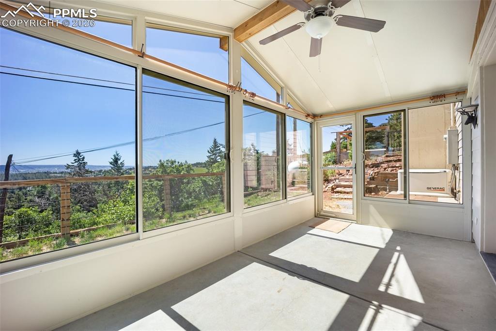 Unfurnished sunroom featuring a ceiling fan and beamed ceiling