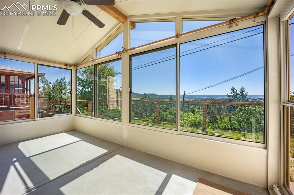 Unfurnished sunroom with a ceiling fan and plenty of natural light