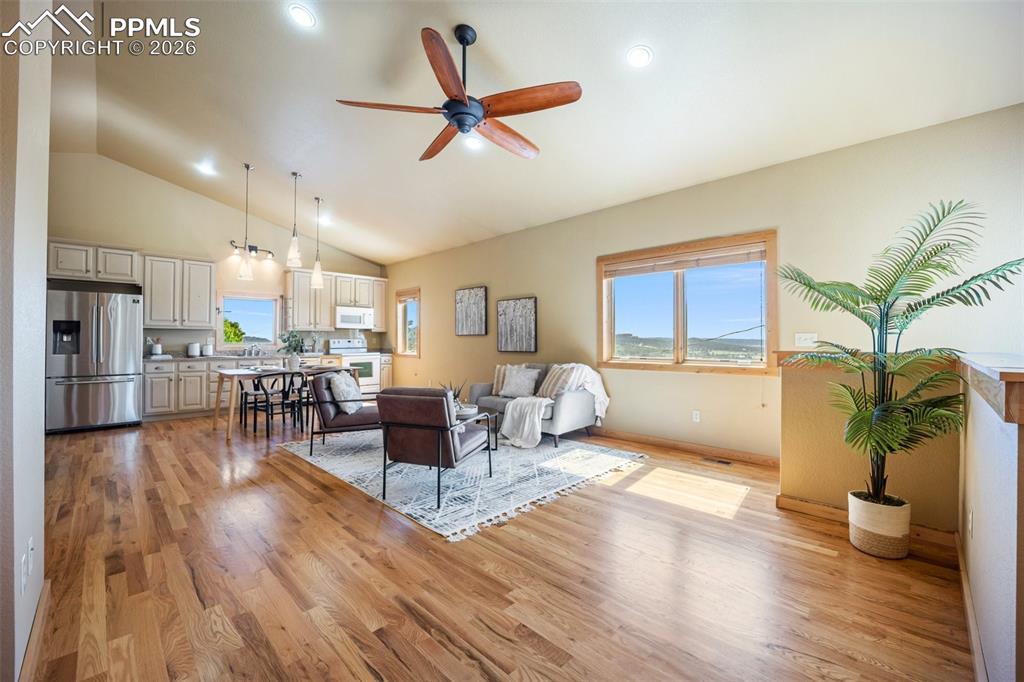 Living area with ceiling fan, light wood-style flooring, vaulted ceiling, and recessed lighting