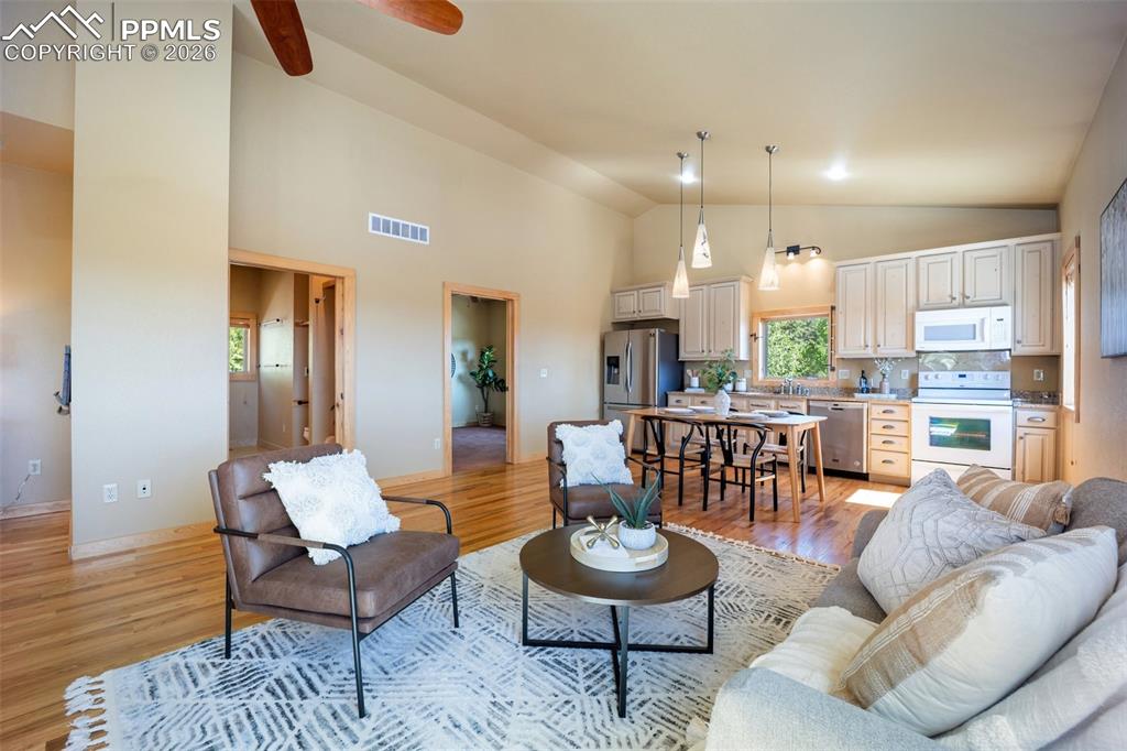 Living area with light wood-type flooring, ceiling fan, and lofted ceiling
