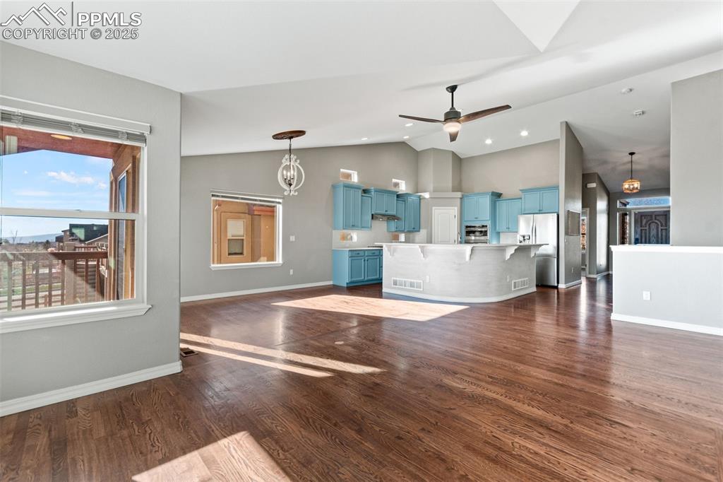 Unfurnished living room featuring dark wood finished floors, vaulted ceiling, ceiling fan, and recessed lighting