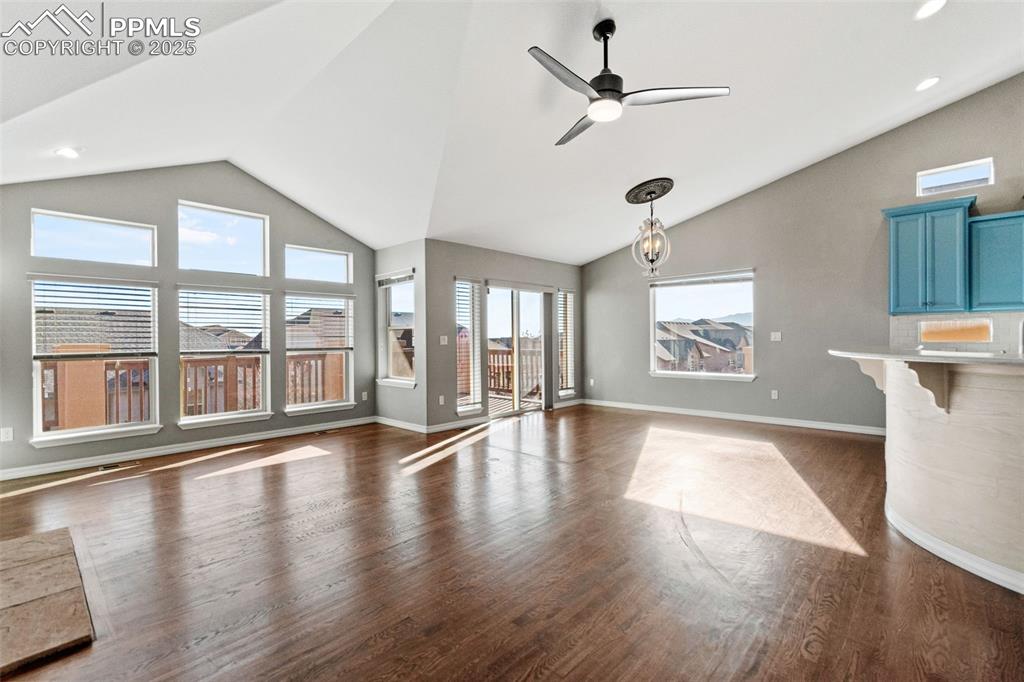 Unfurnished living room with dark wood-style floors, a ceiling fan, and high vaulted ceiling