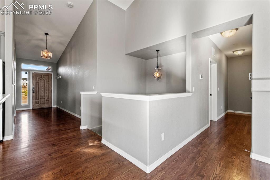 Foyer entrance featuring a chandelier, dark wood-style floors, and high vaulted ceiling