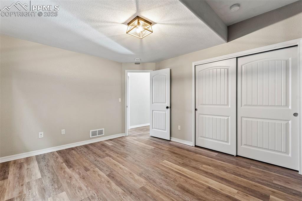 Unfurnished bedroom with light wood-style floors, a closet, and a textured ceiling